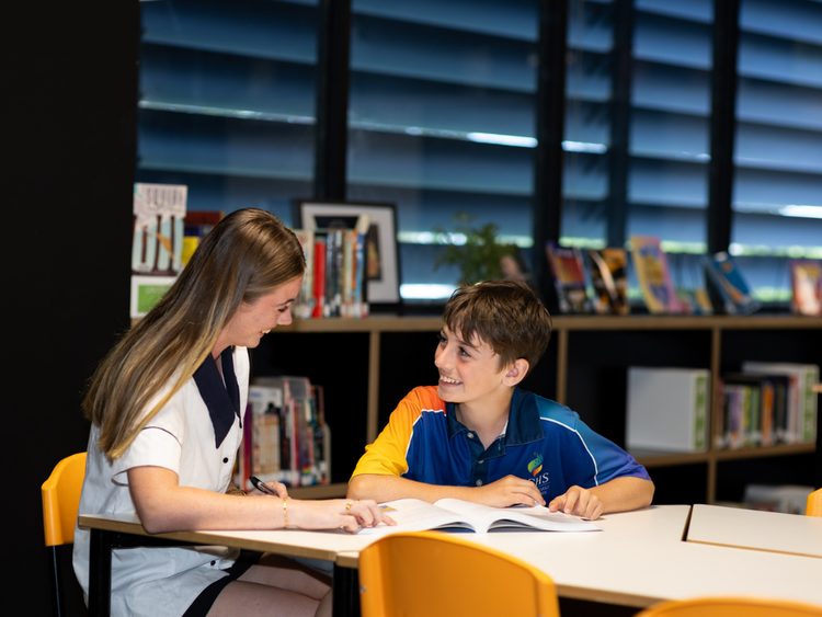 Female senior student working in the library with a male junior student