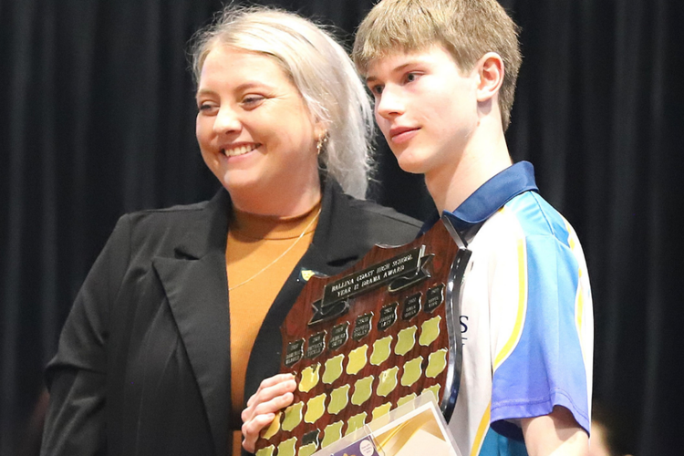 Male student holding a shield and posing with a female staff member