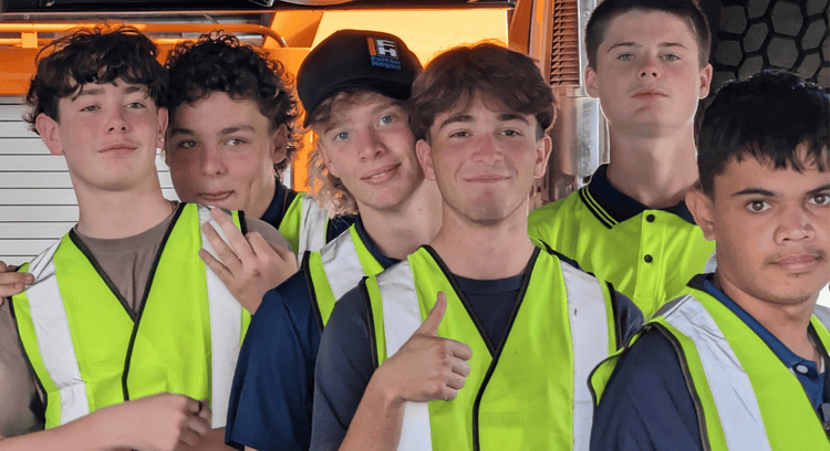 Close-up of six male students standing in close together all wearing yellow high-vis vests