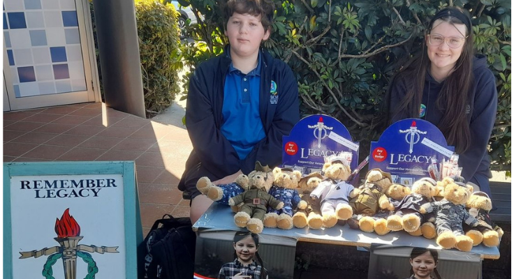 Male and female student selling teddy bears at a Legacy fundraising stand
