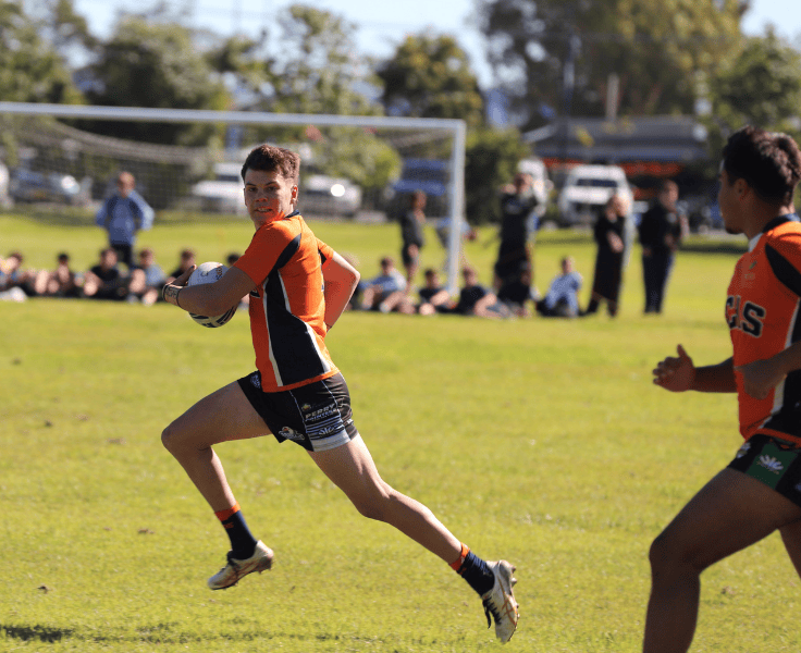 Action shot of rugby league player running with ball looking across to team mate behind him