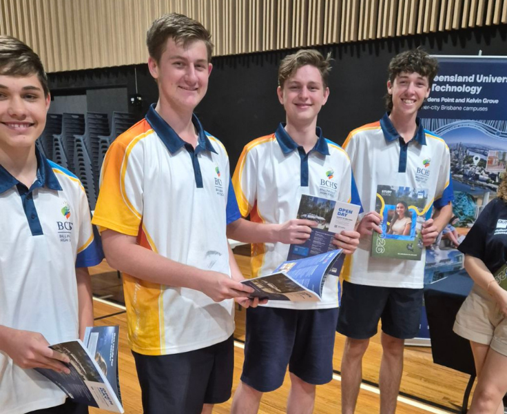 Four male students holding university pamphlets at a careers expo