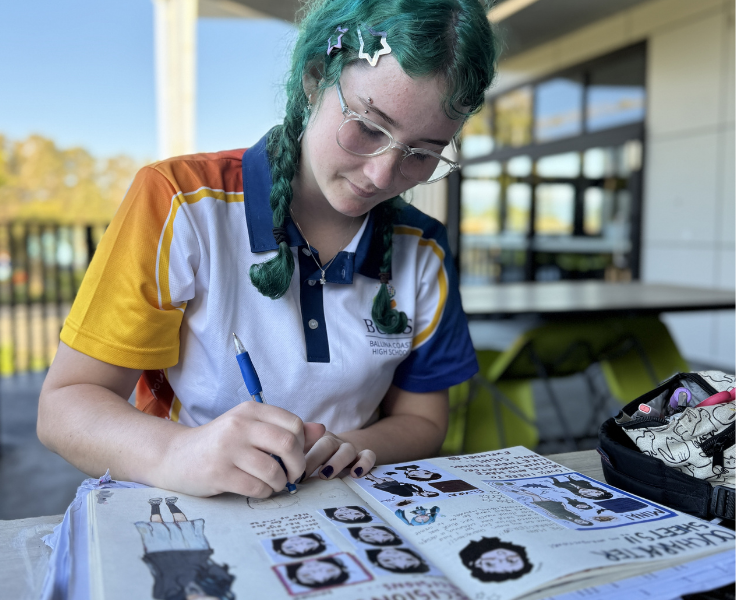 Female student drawing detailed cartoon characters in her art book