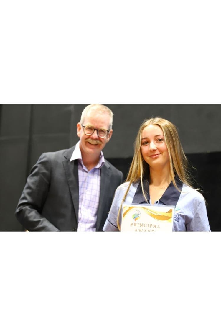 close up of smiling Principal with female student holding a Principals award