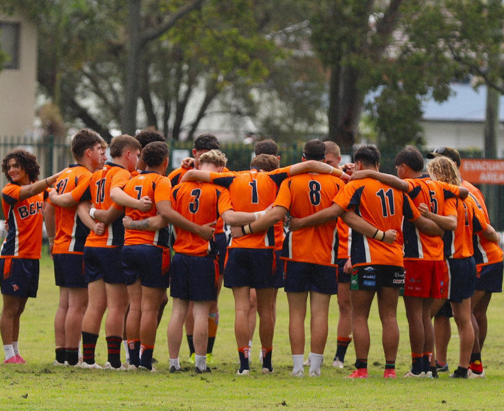 Rugby league team in a pre-game huddle with arms around each other
