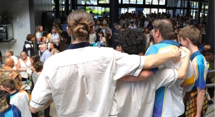 Four male students with their backs to camera and arms around each other