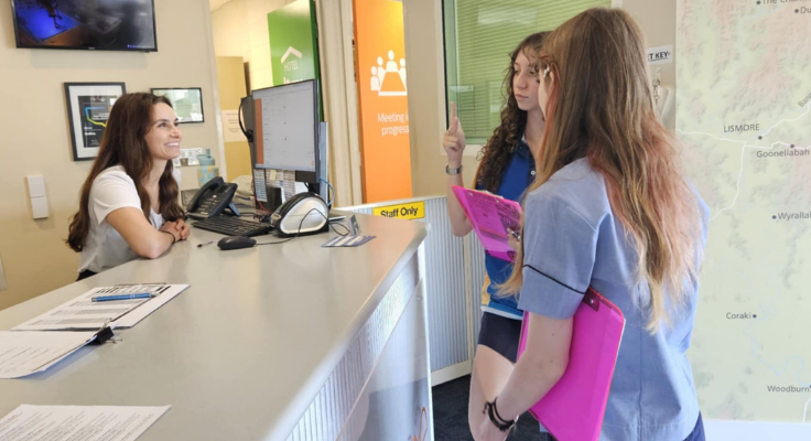 Two students at a local business talking to a smiling receptionist