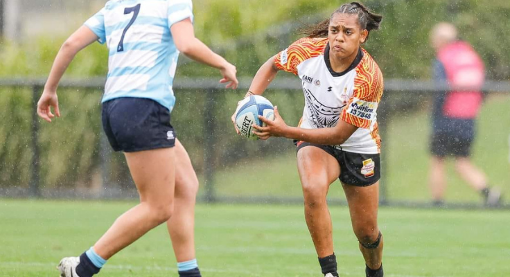 Female rugby league player with football running towards opponent with determination